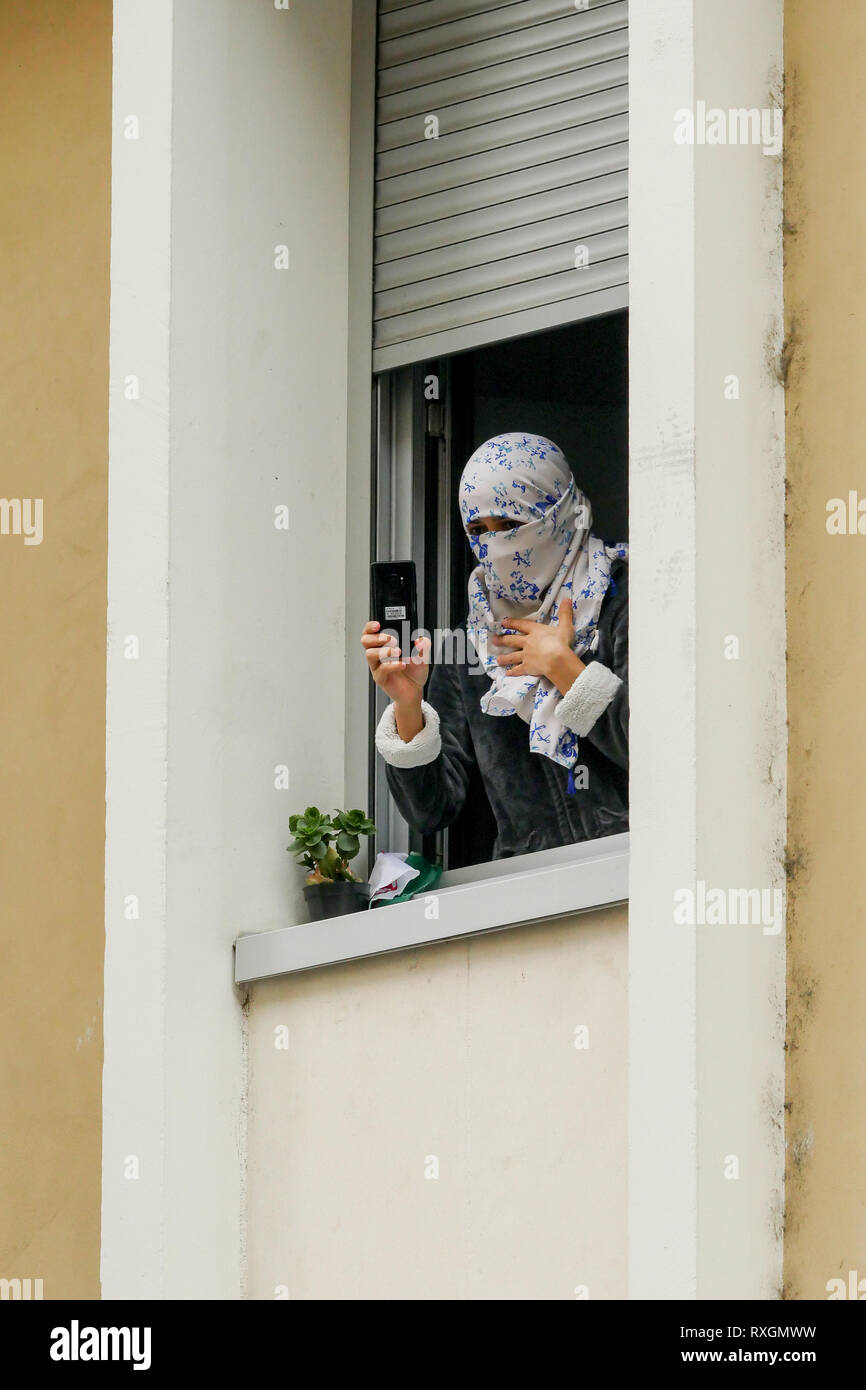 Lyon, France, 9 mars 2019 : Des centaines de membres de la diaspora algérienne de Lyon (Centre-est de la France) sont vus le 9 mars 2019 comme ils mars à Lyon du district pour l'algérien du consulat d'algérie, pour protester contre Abdelaziz Bouteflika 5e candidature à la fonction présidentielle. Ici en photo, un employé du consulat est illustrée comme elle filme les manifestants d'une fenêtre. Crédit photo : Serge Mouraret/Alamy Live News Banque D'Images