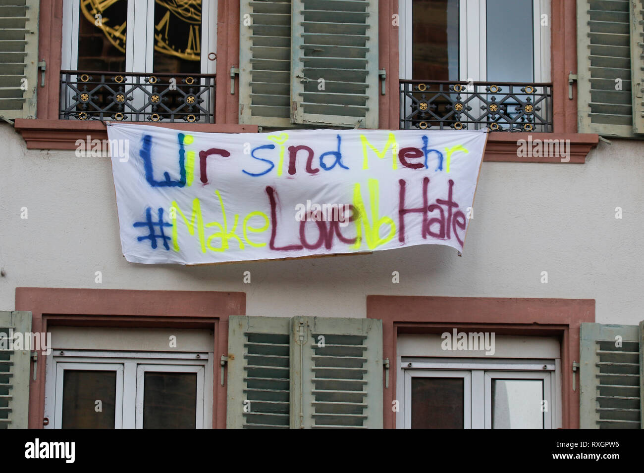 Landau, Allemagne. 9 mars 2019. Une bannière est suspendu à partir de la maison, lire 'Nous sommes plus - Faites l'amour pas de haine". Autour de 80 personnes de organisations d'extrême droite ont protesté dans la ville de Landau dans le Palatinat contre le gouvernement allemand et les migrants. Ils ont également adopté le jaune de la veste jaune français. mouvement de protestation intellectuelle Crédit : Michael Debets/Alamy Live News Banque D'Images