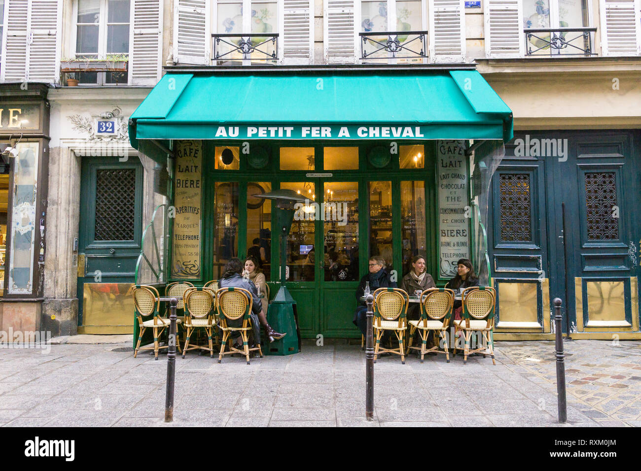 Les clients appréciant le café l'après-midi au café au petit fer a cheval dans la quartier du Marais à Paris, France. Banque D'Images