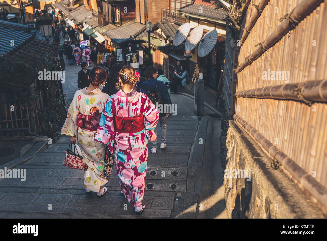 Deux femmes vêtues de kimonos à flâner à travers la vieille ville de Kyoto au Japon au cours de la soirée. Banque D'Images