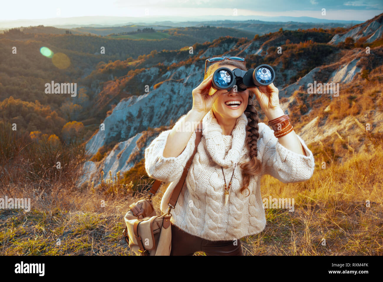 Heureux sain tourisme solo femme en matériel de randonnée avec sac d'été sur la Toscane à Voyage dans la distance avec des jumelles. Banque D'Images