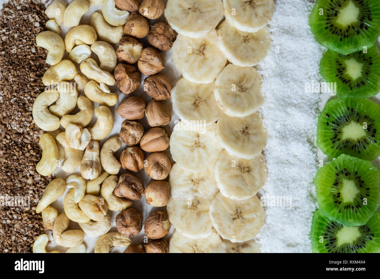 Des ingrédients frais pour un petit-déjeuner sain aliments crus. Kiwi, flocons de noix de coco, noix de cajou et noisettes tourné à partir de ci-dessus, les ingrédients pour un bol à smoothie Banque D'Images