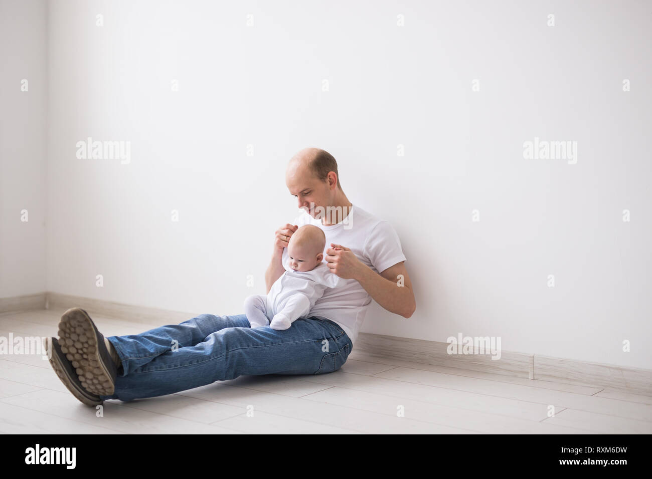 Bébé nouveau-né, la famille et la paternité concept - heureux père chauve holding baby fille à genoux sur fond blanc Banque D'Images