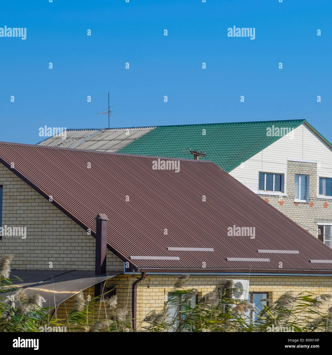 Maisons aux toits en tôle ondulée. Brown et toit vert. Des matériaux modernes pour les toitures Banque D'Images