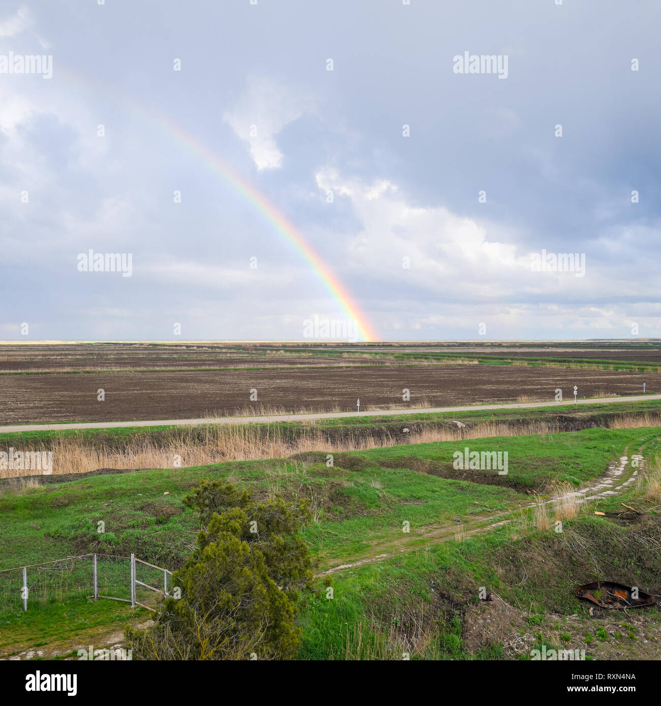 Arc-en-ciel, une vue sur le paysage dans le domaine. Formation de l'arc en ciel après la pluie. La réfraction de la lumière et de l'expansion en termes de spectres. Banque D'Images