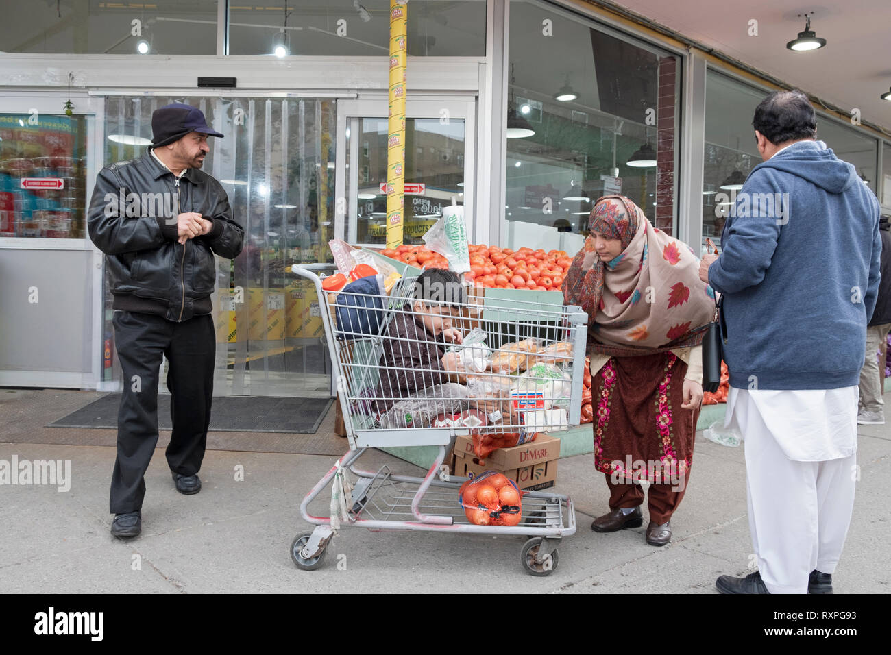 Une scène à l'extérieur de l'Apna Bazaar supermarché avec une famille & enfant dans un panier. Dans la région de Jackson Heights, Queens, New York City Banque D'Images