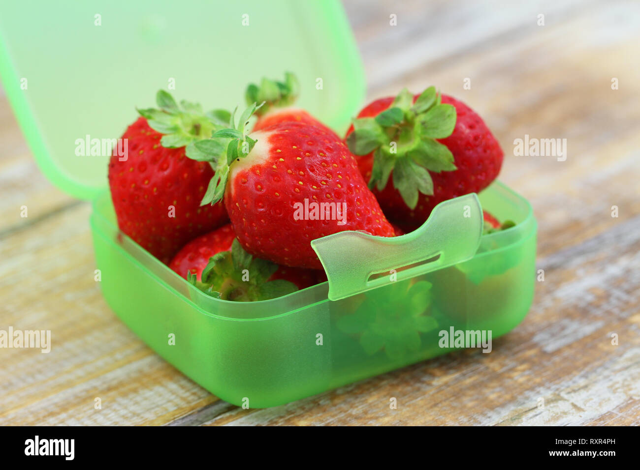 Fraises fraîches dans la boîte en plastique vert surface rustique, gros plan sur Banque D'Images