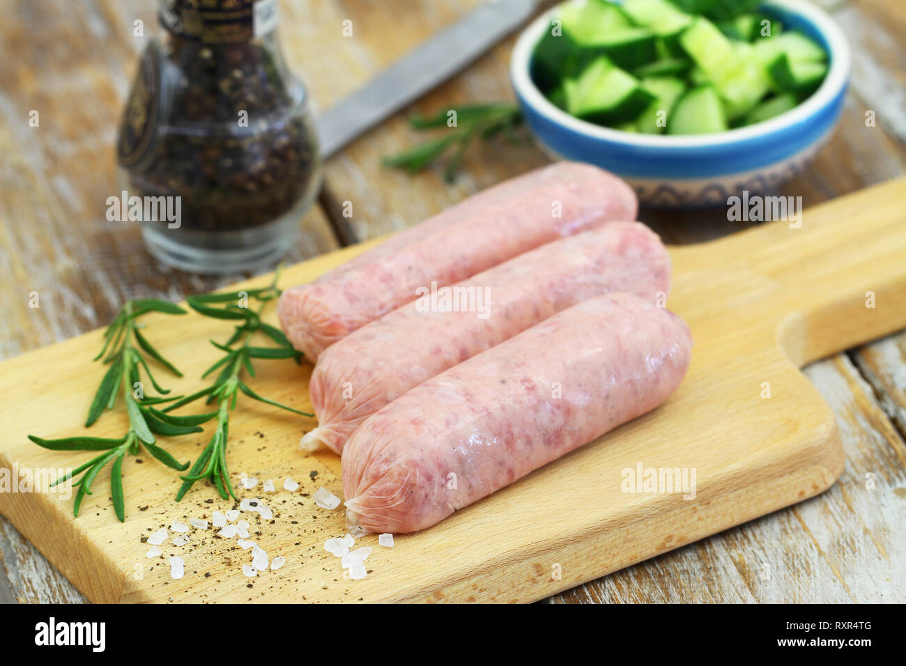 La crus, frais et des saucisses de porc sur planche de bois Banque D'Images