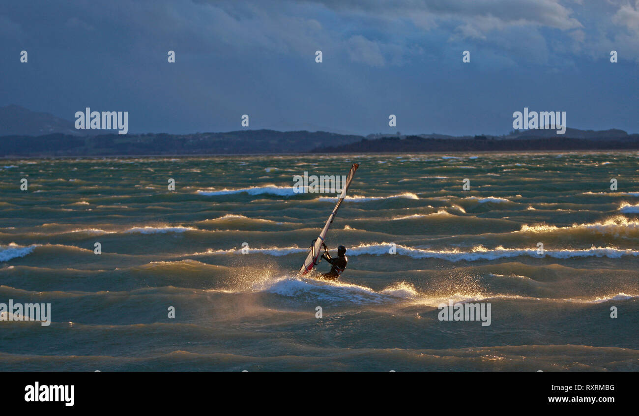 Bernau, Allemagne. Mar 10, 2019. Un surfeur solitaire chasse-neige dans la soirée la lumière à travers les vagues du lac de Chiemsee et vit jusqu'à son nom que le bavarois "mer". Credit : Diether Endlicher/dpa/Alamy Live News Banque D'Images