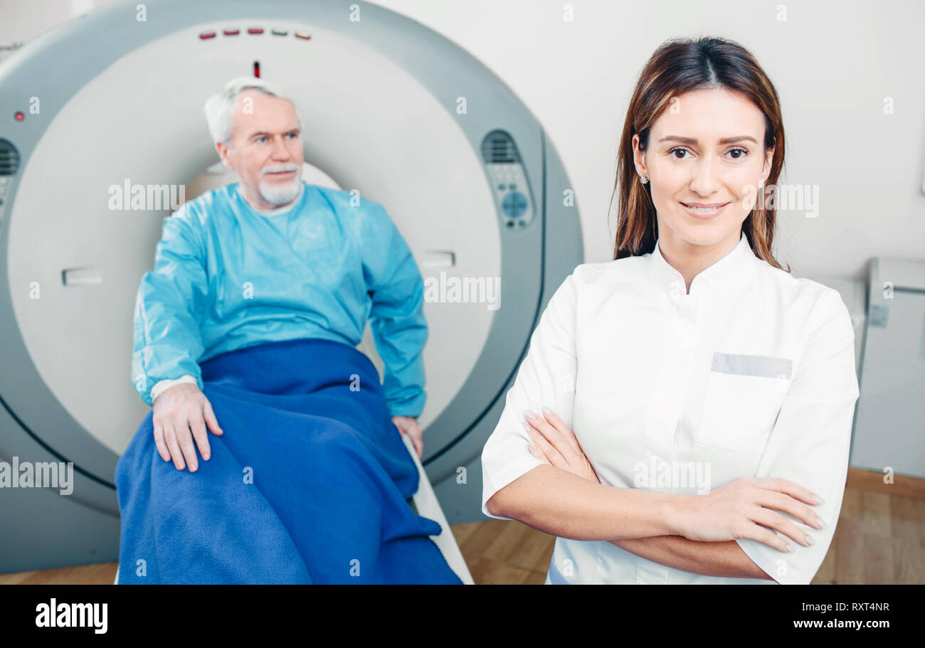 Médecin radiologue, souriant tout en regardant la caméra. Assis derrière son senior patient. Scanner à l'hôpital Banque D'Images