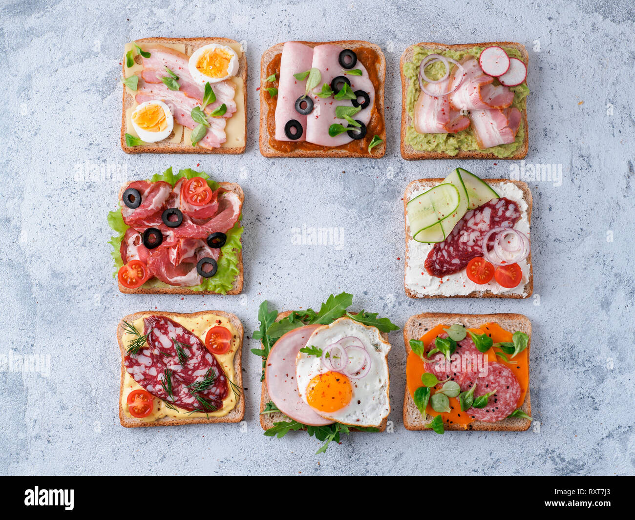 Ensemble de huit différents sandwiches avec de la viande en forme carrée,copier du texte dans l'espace centre.Vue supérieure ou télévision lay.assortiment de toasts viande sur le ciment gris background.idée,concept créatif pour charcutier Banque D'Images