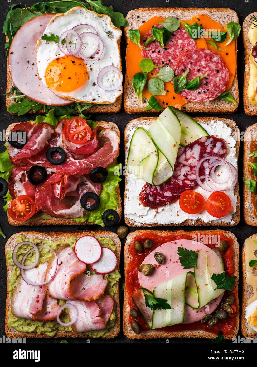 Ensemble de huit différents sandwiches avec de la viande en forme carrée. Vue de dessus ou de télévision. Toasts viande assortiment sur fond noir. Idée, concept créatif pour charcutier Banque D'Images