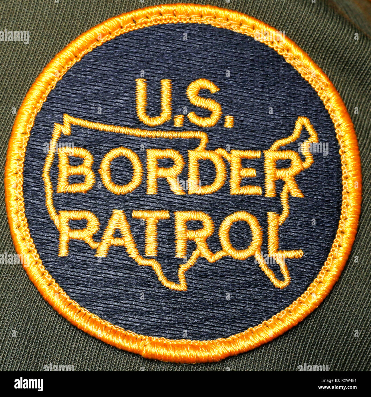 Badge de la patrouille frontalière des États-Unis montrant l'insigne officiel en forme de bouclier circulaire de l'USBP, avec le lettrage or « U.S. Border Patrol » et un contour stylisé de la zone continentale des États-Unis en jaune sur un sol bleu marine, utilisé par les agents de l'agence fédérale chargée de la sécurité des frontières. Photographie tirée d'un badge officiel de patrouille frontalière Banque D'Images