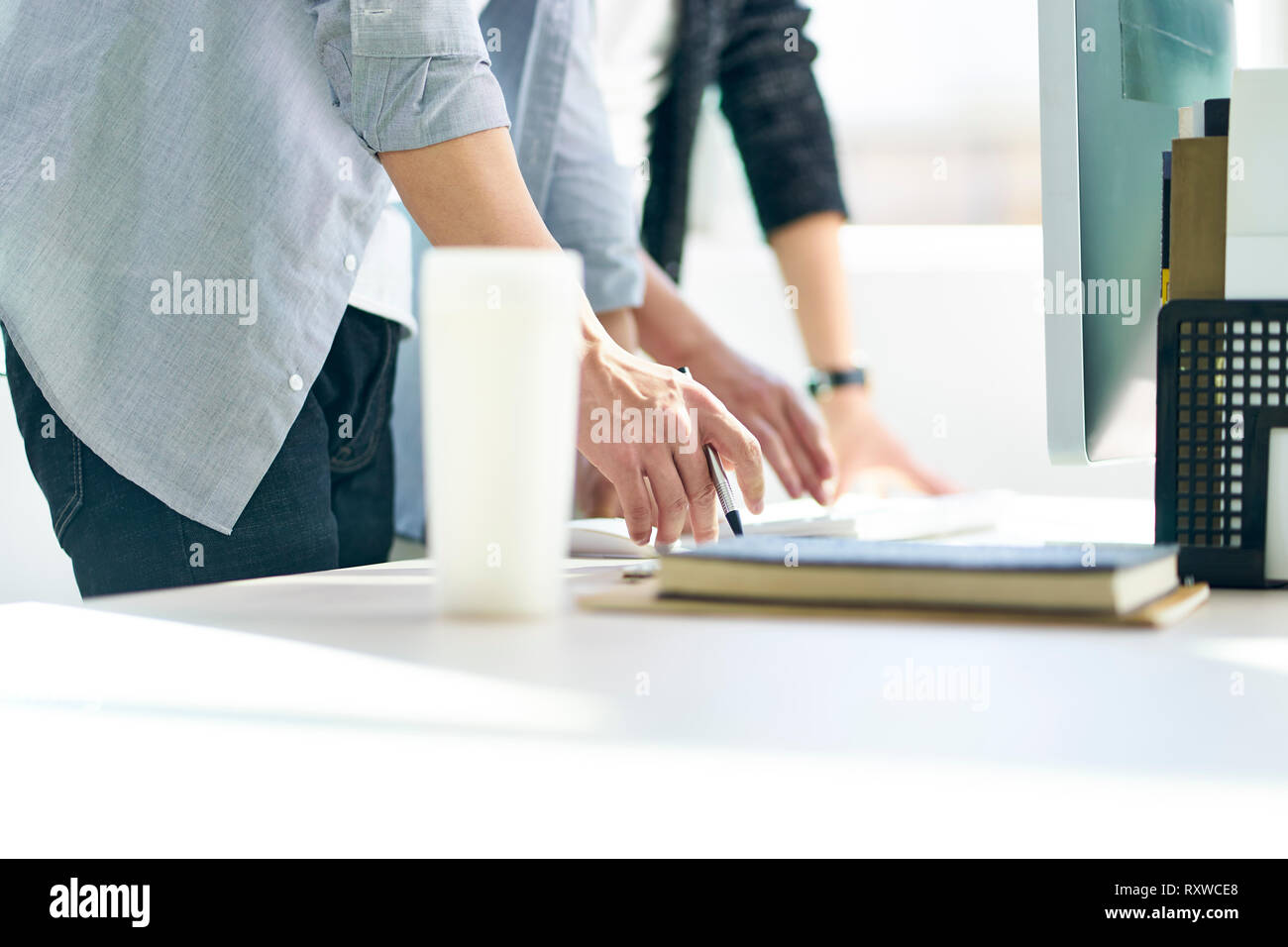 Deux jeunes gens d'affaires asiatiques travaillant ensemble en face de l'ordinateur de bureau en bureau. Banque D'Images