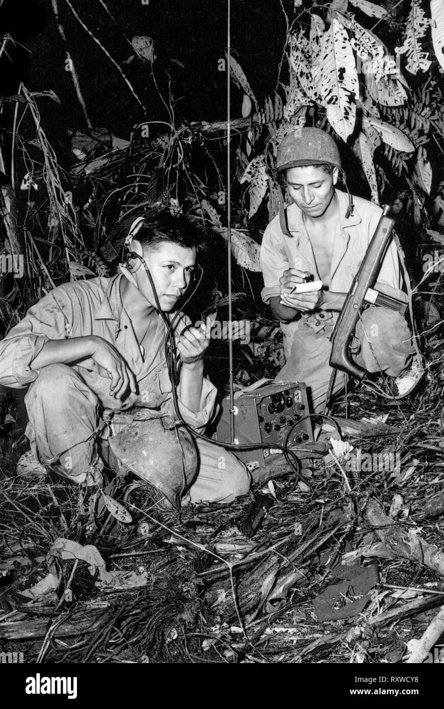 Code Navajo d'étagère Le Caporal Henry Bake, Jr., (à gauche) et le soldat de première classe George H. Kirk (à droite), servant avec une unité de signal maritime, l'exploitation d'un poste radio portatif dans une clairière, ils viennent d'hacked dans la jungle dense près derrière les lignes de front sur l'île de Bougainville en Papouasie Nouvelle Guinée au cours de la Seconde Guerre mondiale en décembre 1943. Banque D'Images