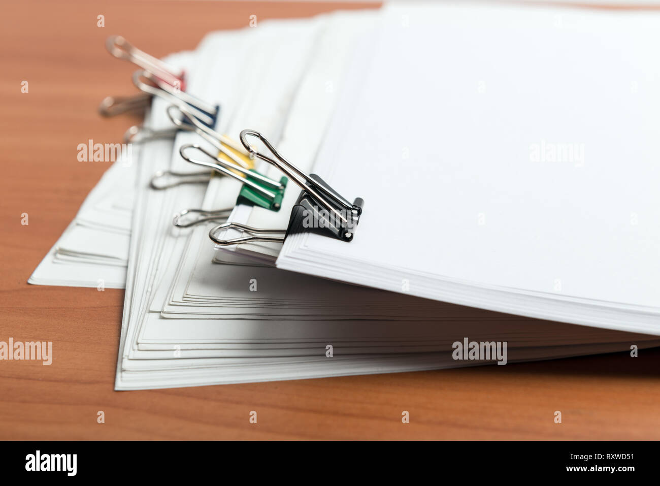 Papier blanc Modèle de document avec des clips de couleur métal sur table de travail Vue de côté Banque D'Images