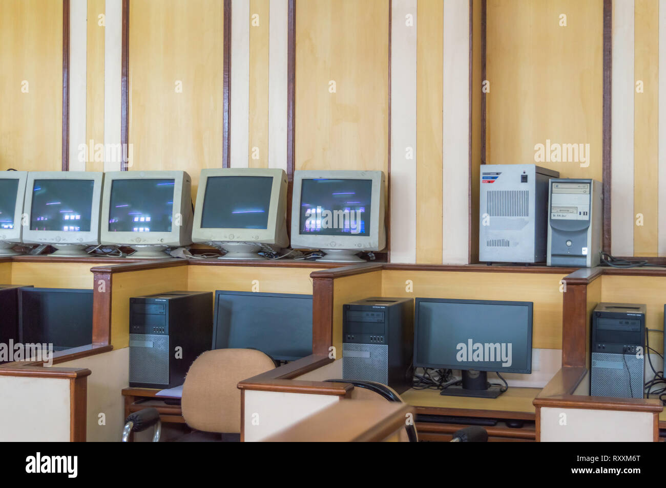 Pièces de moniteurs et moniteurs fonctionnels dans le laboratoire informatique d'une école avec cabines individuelles et des chaises Banque D'Images