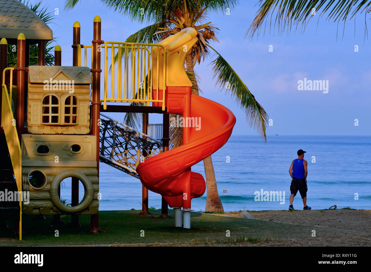 Une plage goer passant d'une aire de jeux pour enfants à Karon Beach, Phuket, Thailand Banque D'Images