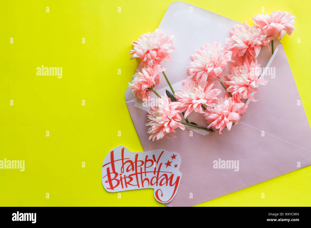 La composition de fleurs de fête, invitation sur l'artisanat sur l'enveloppe le fond jaune. Vue de dessus.Joyeux Anniversaire carte postale.printemps composition. un bouquet de Banque D'Images