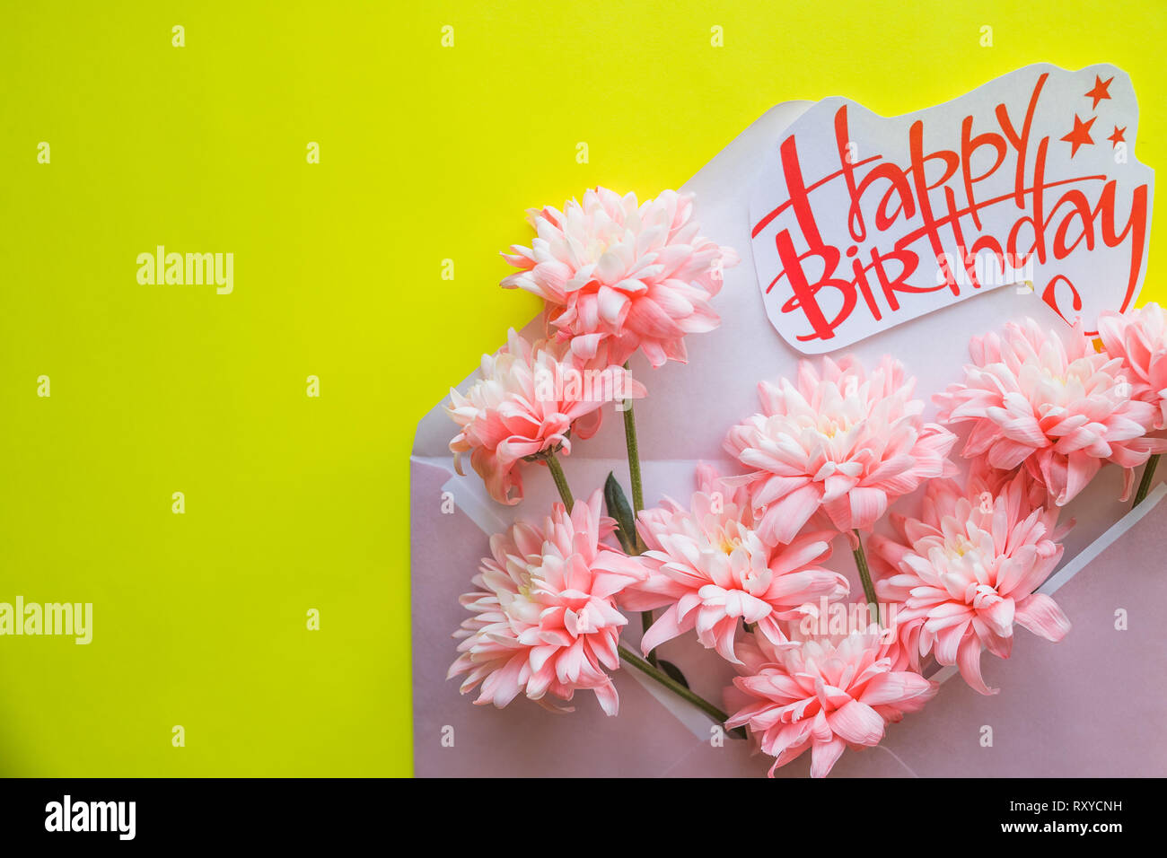 La composition de fleurs de fête, invitation sur l'artisanat sur l'enveloppe le fond jaune. Vue de dessus.Joyeux Anniversaire carte postale.printemps composition. un bouquet de Banque D'Images