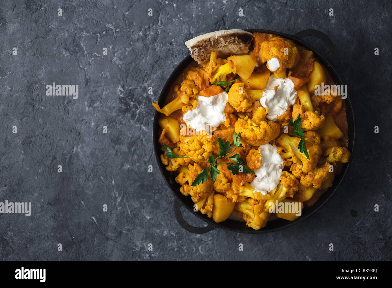 Cuisine asiatique végétarienne. Curry de chou-fleur sur pan pierre sombre arrière-plan avec copie espace vue d'en haut. Concept d'aliments sains et savoureux Banque D'Images