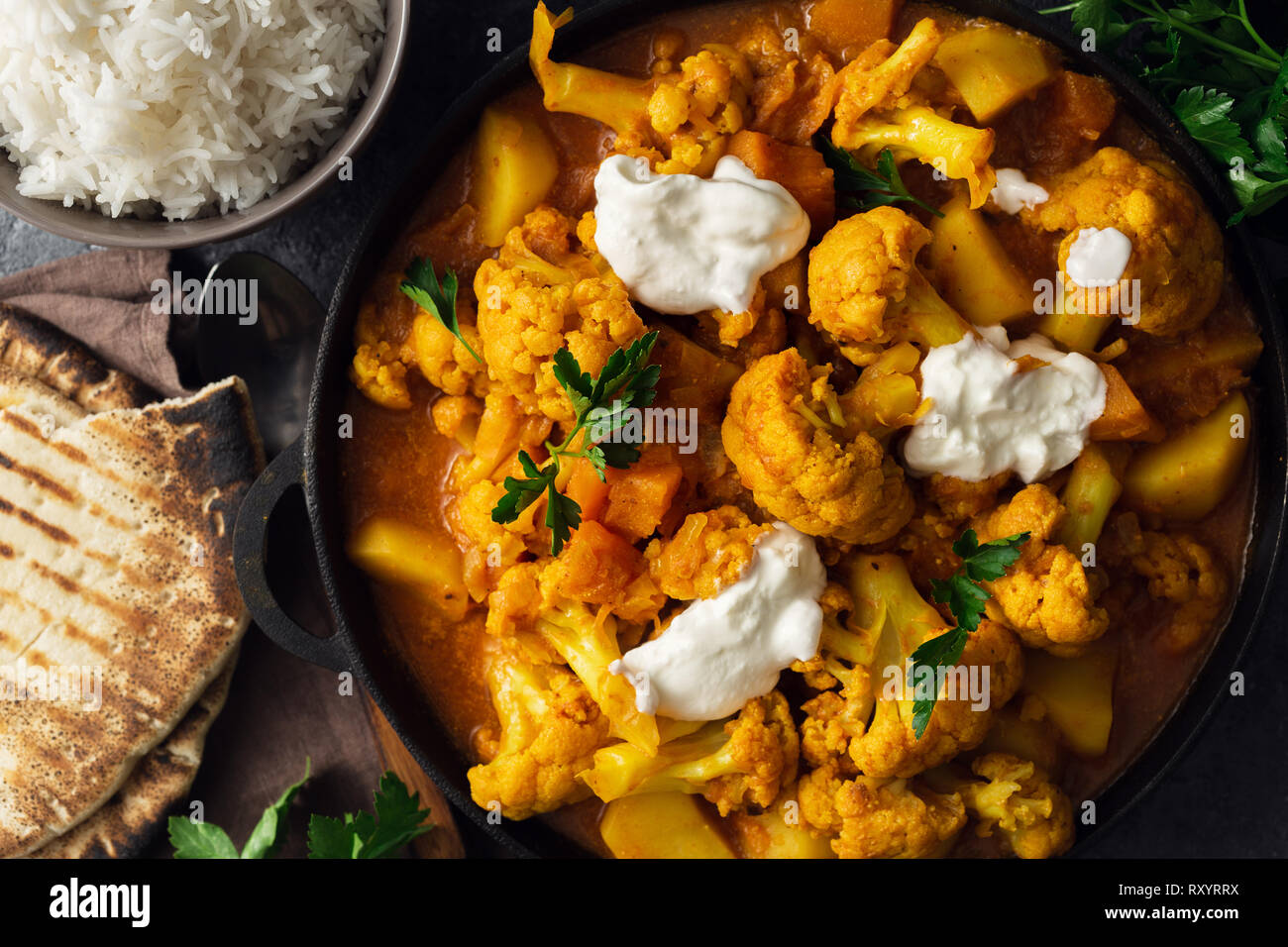 La nourriture indienne végétarienne. Curry de chou-fleur avec du riz basmati et du pain naan sur pierre sombre contexte Vue d'en haut. Concept d'aliments sains et savoureux Banque D'Images