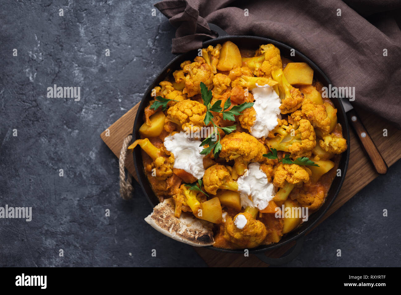 Cuisine asiatique végétarienne. Curry de chou-fleur sur une pierre sombre arrière-plan avec copie espace vue d'en haut. Concept d'aliments sains et savoureux Banque D'Images