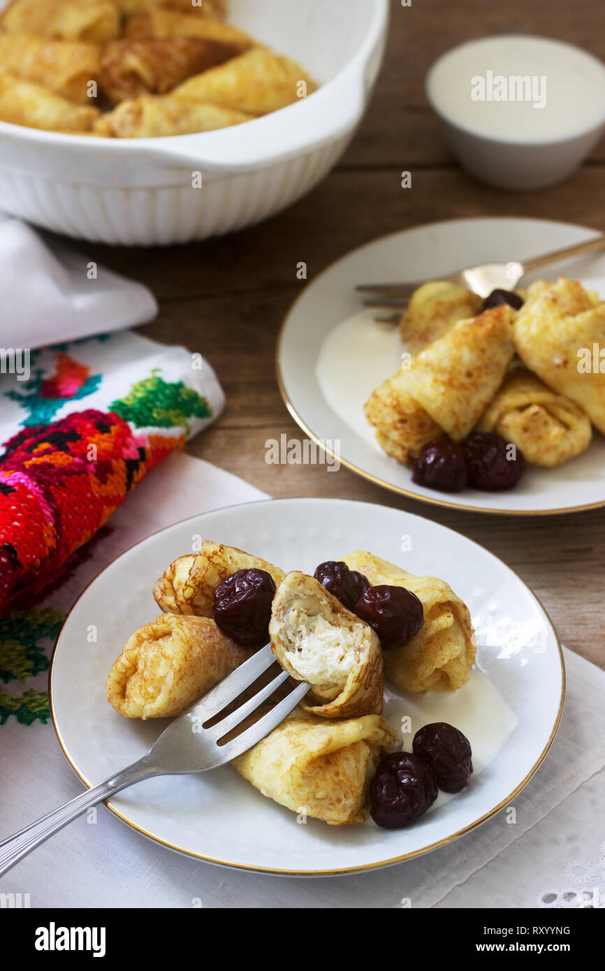 Crêpes maison farcies au fromage blanc et aux raisins secs, servi avec crème sure et cerise. Moldave traditionnelle roumaine ou dessert, fo sélective Banque D'Images