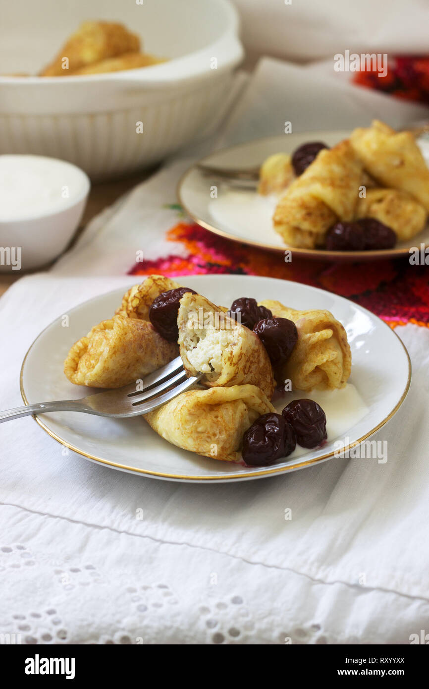 Crêpes maison farcies au fromage blanc et aux raisins secs, servi avec crème sure et cerise. Moldave traditionnelle roumaine ou dessert, fo sélective Banque D'Images