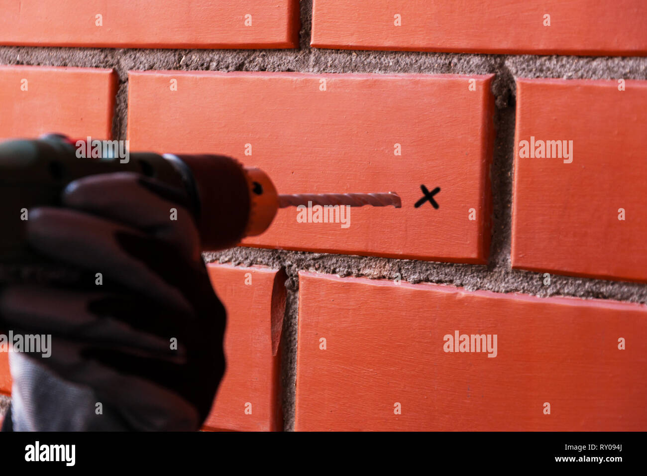 Percer avec une perceuse sur l'arrière-plan d'un mur de brique rouge. Sur  la brique de passage pour le perçage. Concept de bricolage Photo Stock -  Alamy