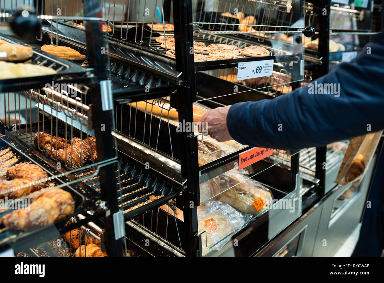 Croissant frais sur l'étagère de pain en magasin. Un homme prend une nouvelle avec une spatule. Concept alimentaire. Banque D'Images