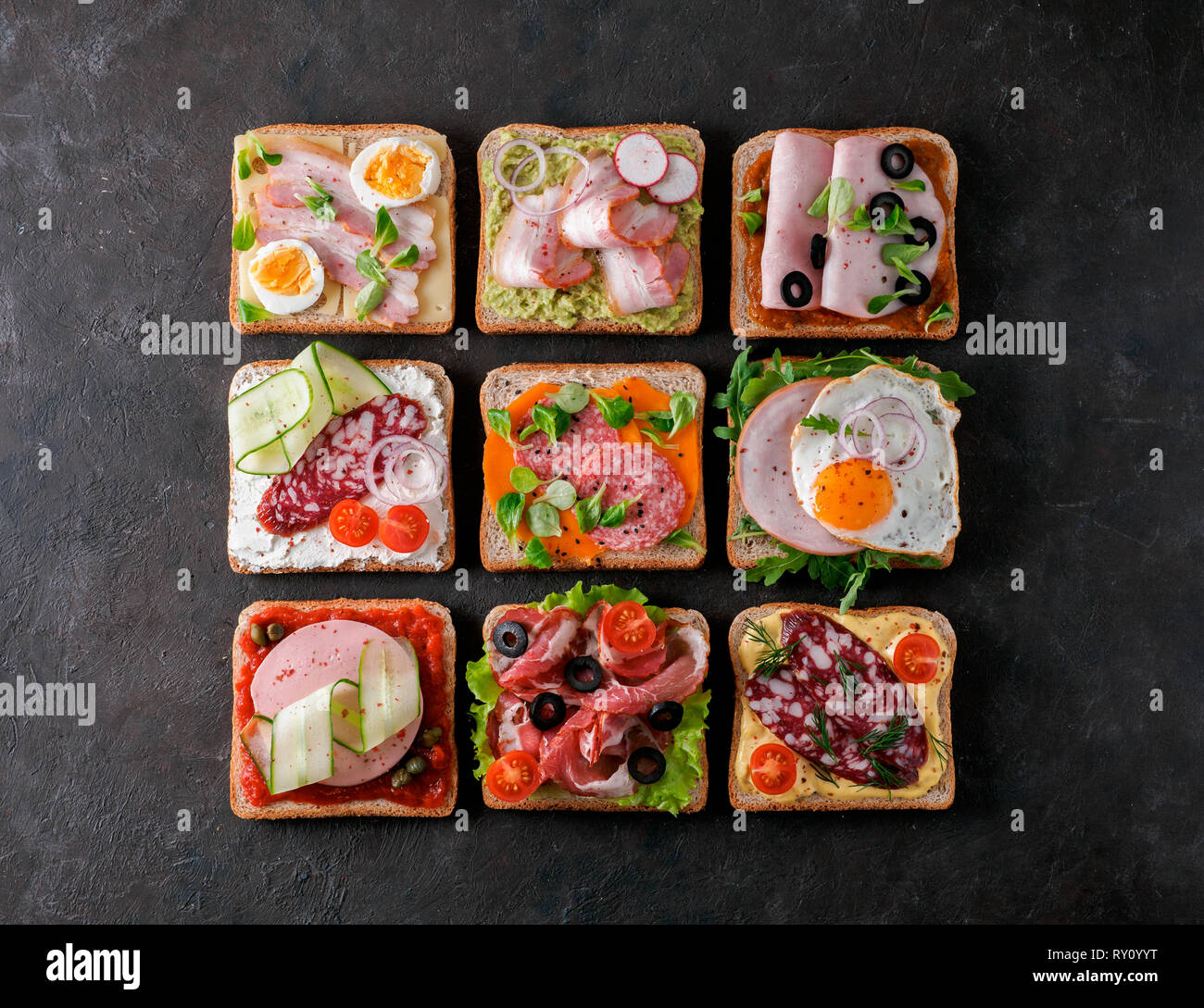 Ensemble de huit différents sandwiches avec de la viande en forme carrée. Vue de dessus ou de télévision. Toasts viande assortiment sur fond noir. Idée, concept créatif pour charcutier Banque D'Images
