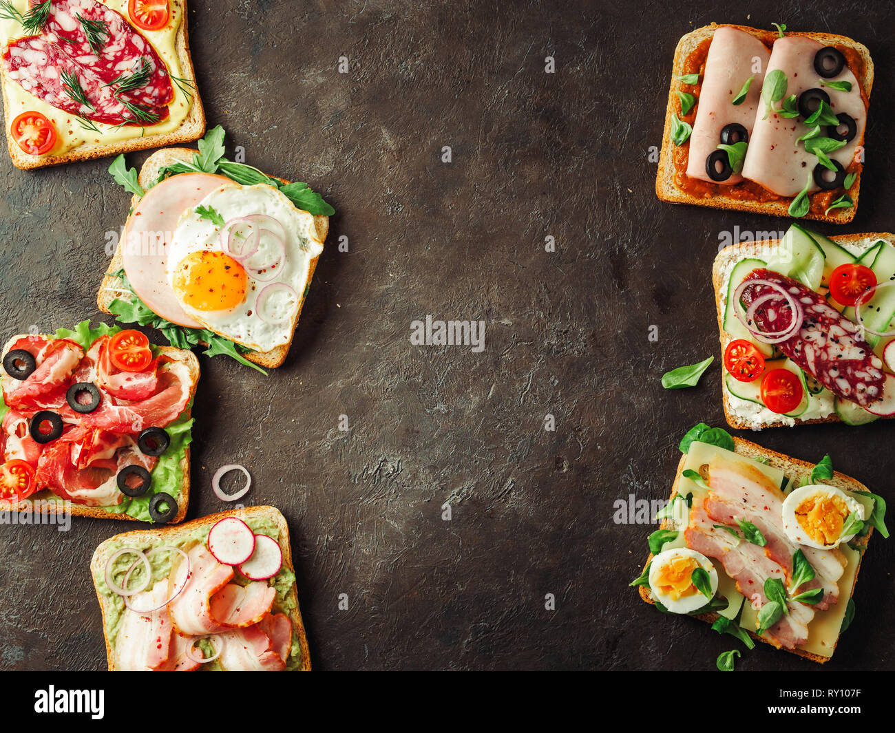 Ensemble de huit différents sandwiches avec de la viande, pour la conception de l'espace de copie ou de texte dans le centre. Vue de dessus ou de télévision. Toasts viande assortiment sur fond noir. Idée, concept créatif pour charcutier Banque D'Images