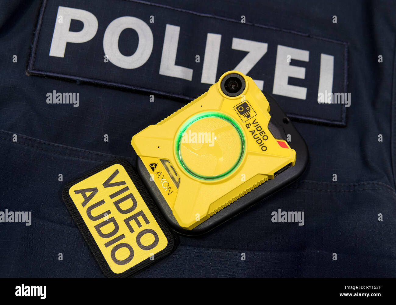 ILLUSTRATION - 11 mars 2019, Bavaria, Munich : un soi-disant Bodycam est allongé sur une police bulletproof vest avant le début d'une conférence de presse sur l'introduction, à l'échelle de Bavarois Bodycams à la police. Dans un test pilote, la police bavaroise testé les caméras effectuée directement sur le corps des officiers de police à Munich, Augsbourg et de Rosenheim. Environ 300 policiers avaient testé trois modèles différents de patrouilles. Photo : Peter Kneffel/dpa Banque D'Images