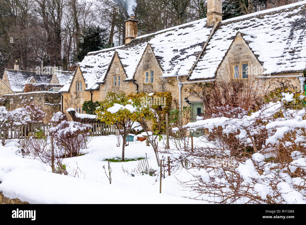 Cottages en pierre de Cotswold et jardins couverts de neige à Bibury Gloucestershire, Royaume-Uni Banque D'Images