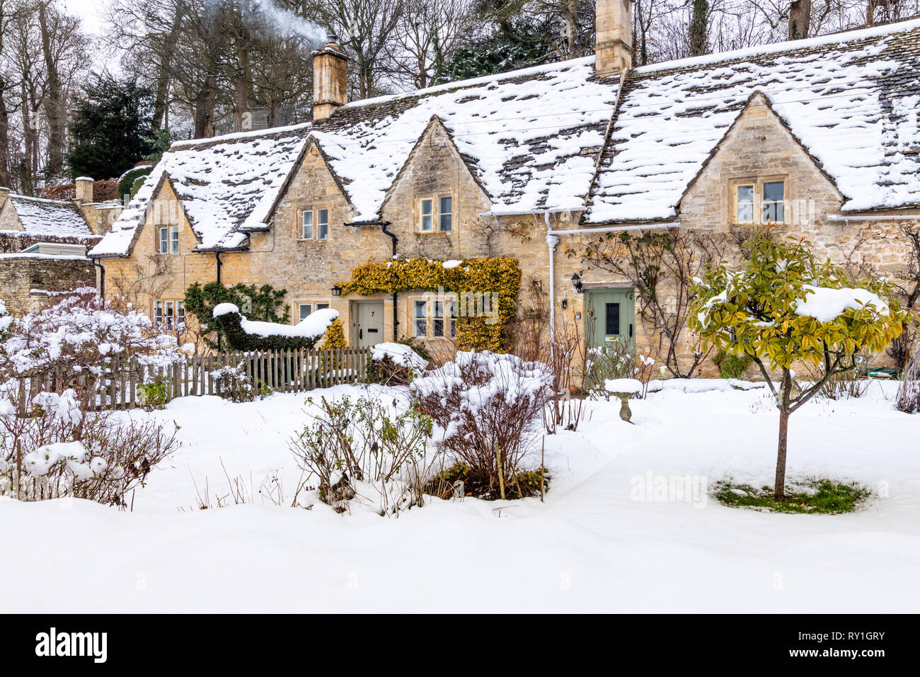 Cottages en pierre de Cotswold et jardins couverts de neige à Bibury Gloucestershire, Royaume-Uni Banque D'Images