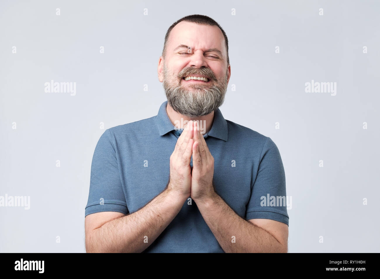 Homme barbu d'âge mûr inscrivez-vous les mains ensemble la mendicité pour lui demander pardon de l'aide Banque D'Images