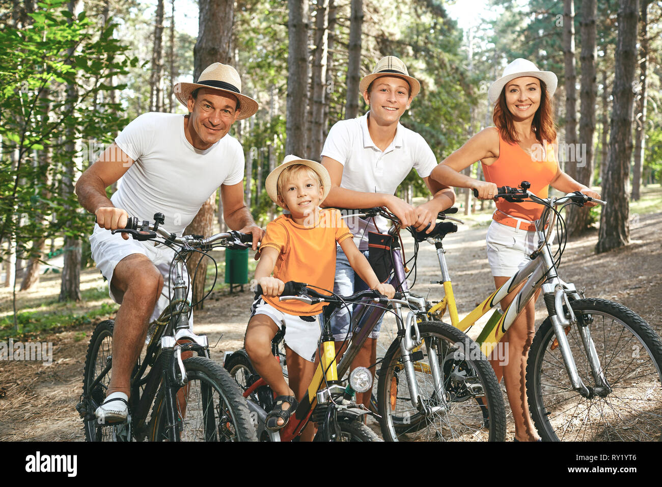 Famille heureuse sur les bicyclettes pour une promenade en parc. Banque D'Images