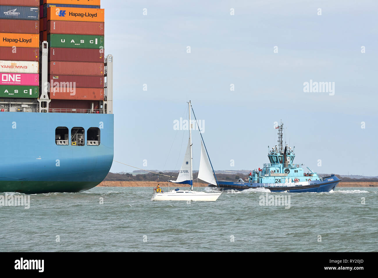 Le petit bateau à voile, DRIFTER, passe à proximité de la porte-conteneurs géant, MOL, hommage à son entrée dans le Port de Southampton après un voyage de 26 jours. Banque D'Images