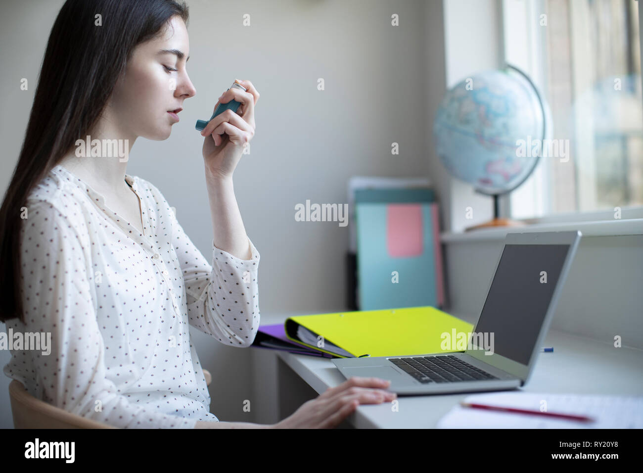 Teenage Girl Using Asthma inhaler l'étude à la maison Banque D'Images