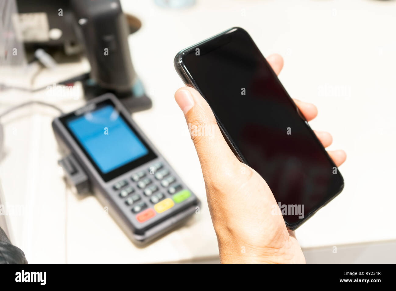 Un homme main tenant et à l'aide de smart phone pour payer les biens à une caissière. Concept commercial. Banque D'Images