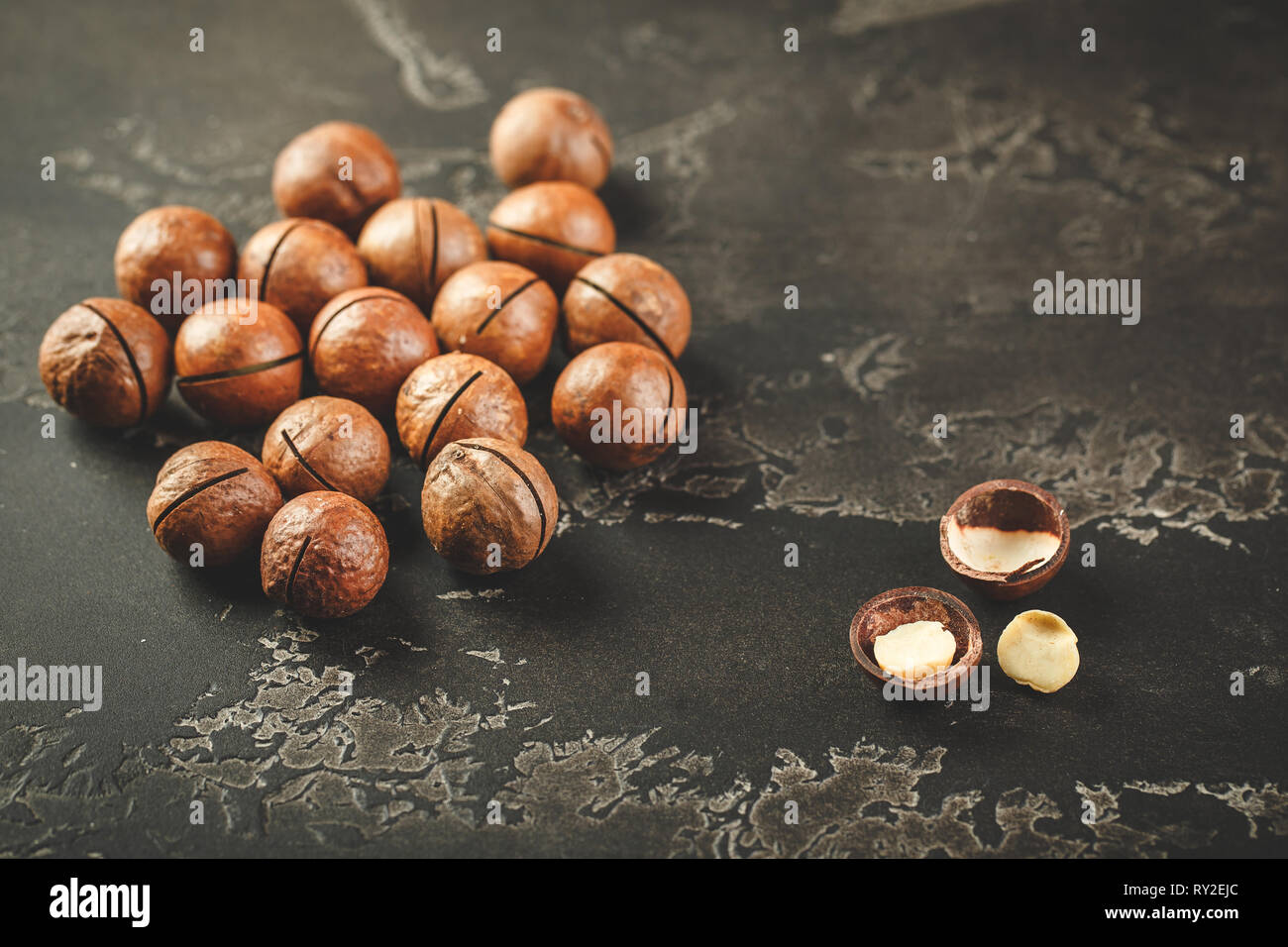 Macadamia bio dans cocrete sur fond sombre. Banque D'Images