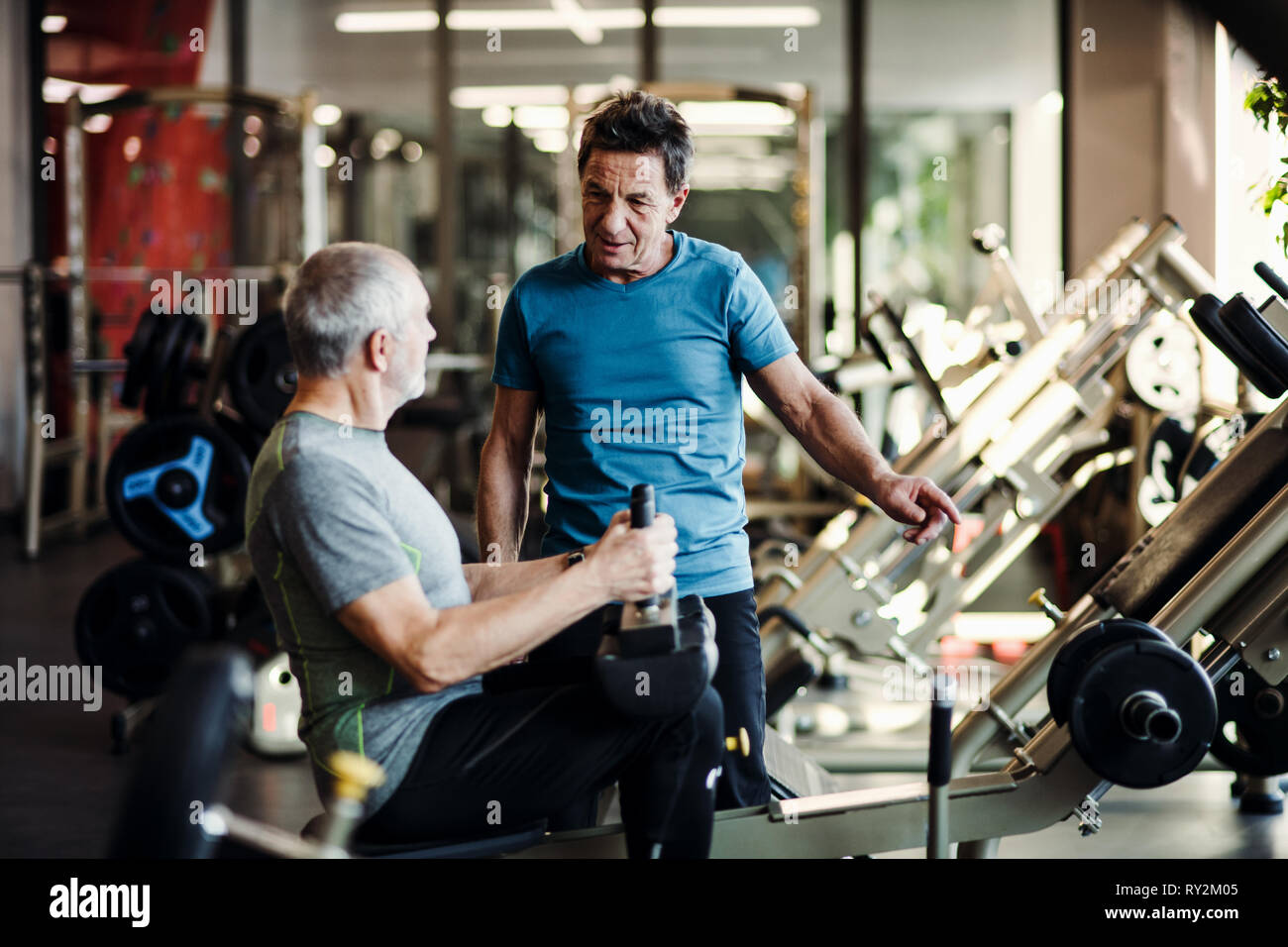 Un homme avec un formateur de jeunes faisant l'exercice d'entraînement de force dans une salle de sport. Banque D'Images