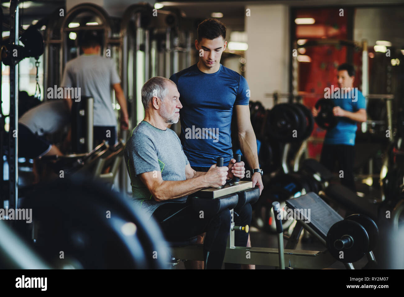 Un homme avec un formateur de jeunes faisant l'exercice d'entraînement de force dans une salle de sport. Banque D'Images