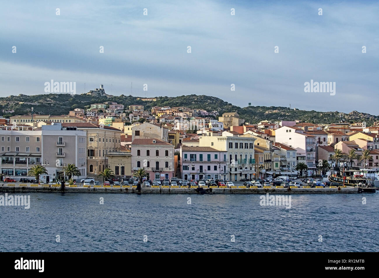 ISOLA MADDALENA, Sardaigne, Italie - 7 mars 2019 : petit ferry port et front de mer bordée de palmiers bâtiments sur 7 Mars 2019 à Isola Maddalena en Sardaigne, je Banque D'Images