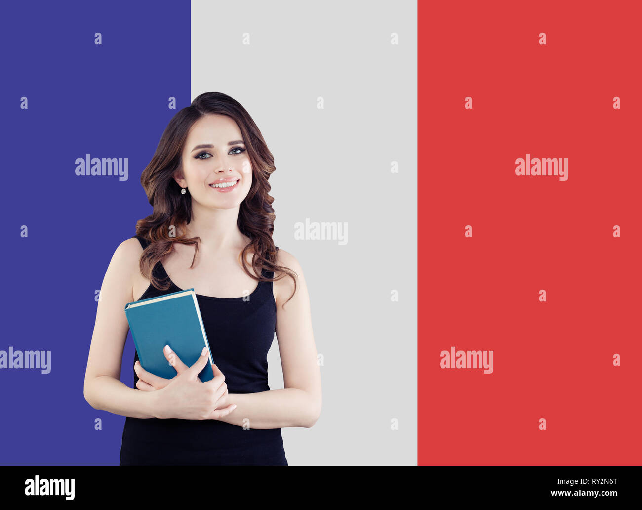 Portrait de jeune femme souriante avec livre sur le drapeau français. Déplacements en France et à l'étude dans l'école de langue française Banque D'Images