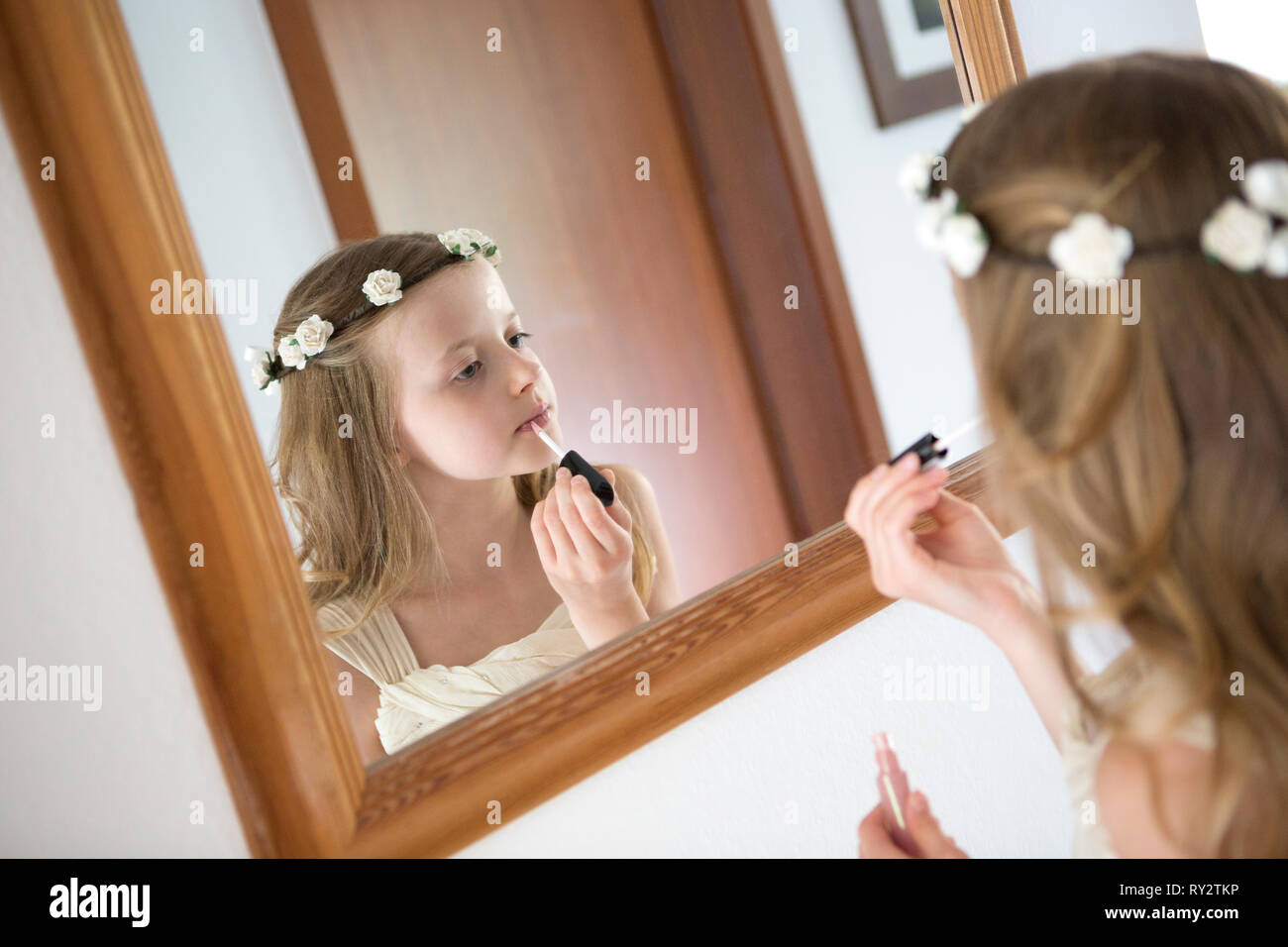 Jeune demoiselle d'un brillant à lèvres mise sur en face d'un miroir Banque D'Images