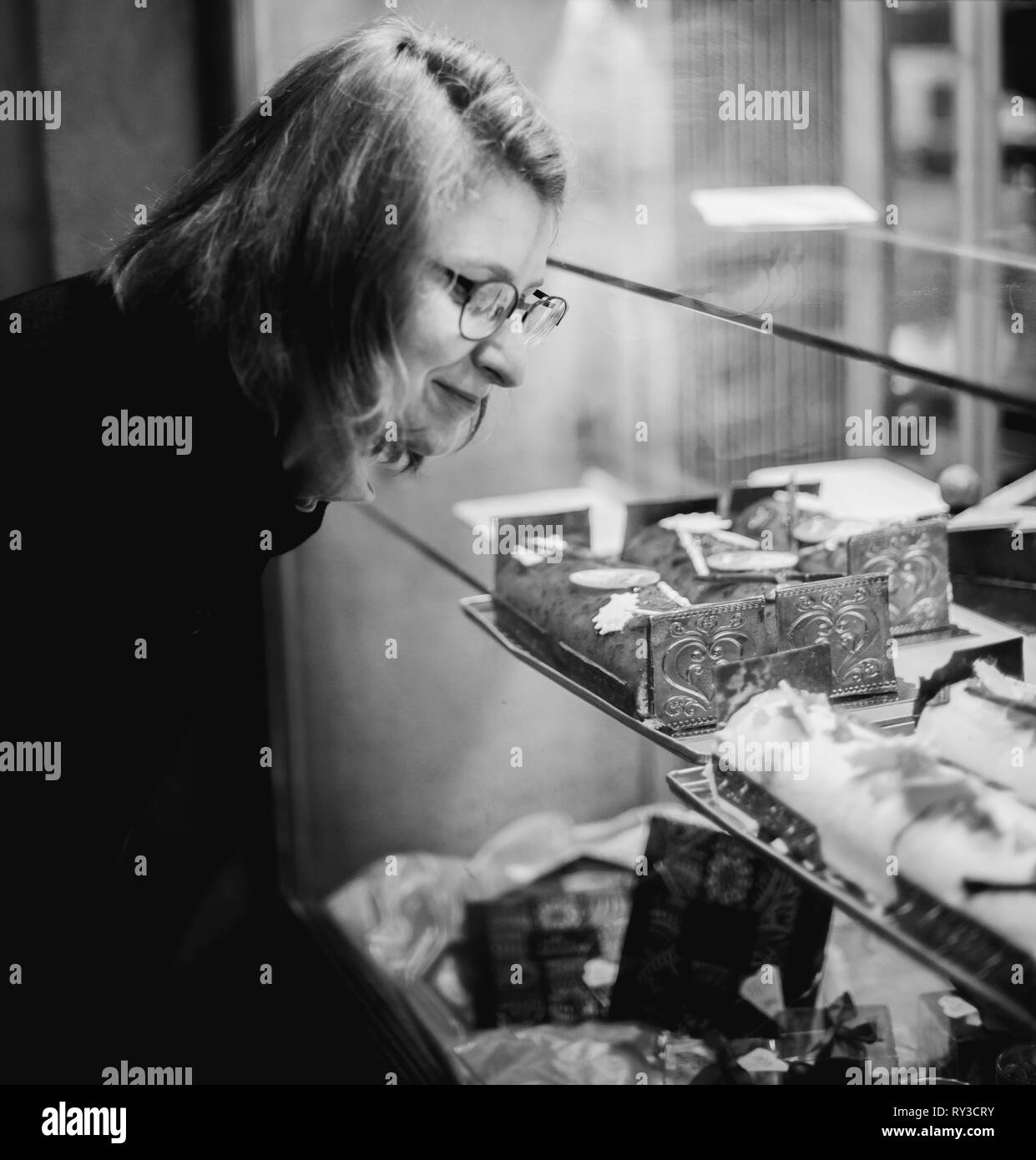 Achat femme bonbons par la pâtisserie boulangerie vitrine en français ville pendant les vacances d'hiver noël Banque D'Images