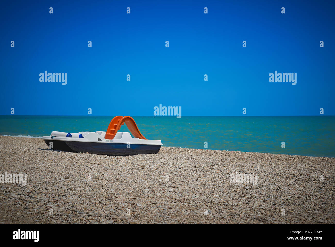 Un pédalo bleu et blanc avec une orange glisser sur une plage le long de la côte de l'Italie au cours de l'été. Le format paysage. Saison et maison de concept. Banque D'Images