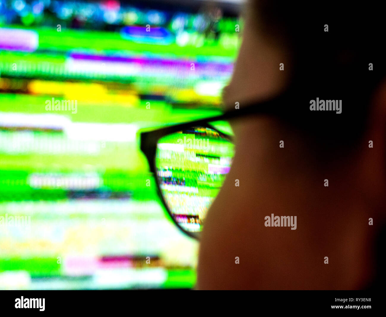 Vue arrière de l'optique lunettes femme portant à la recherche au mauvais signal bruit statique de son écran de télévision TVN numérique Banque D'Images